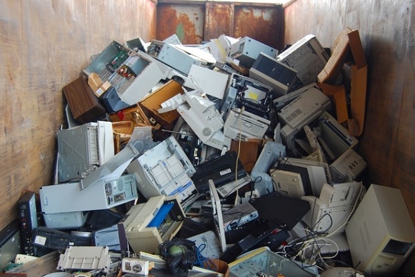 computers printers piled up by electronics waste collectors compactor