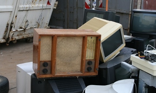 an old radio and CRT monitor at a scrapyard, in a pile